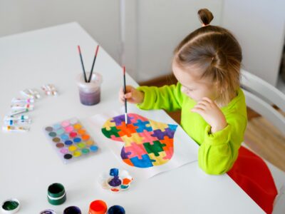 A girl draws drawing for autistic children with picture of heart from puzzles.