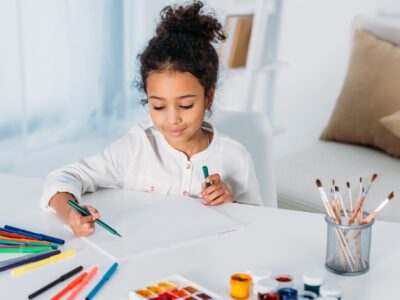 adorable african american kid drawing with felt pens at home