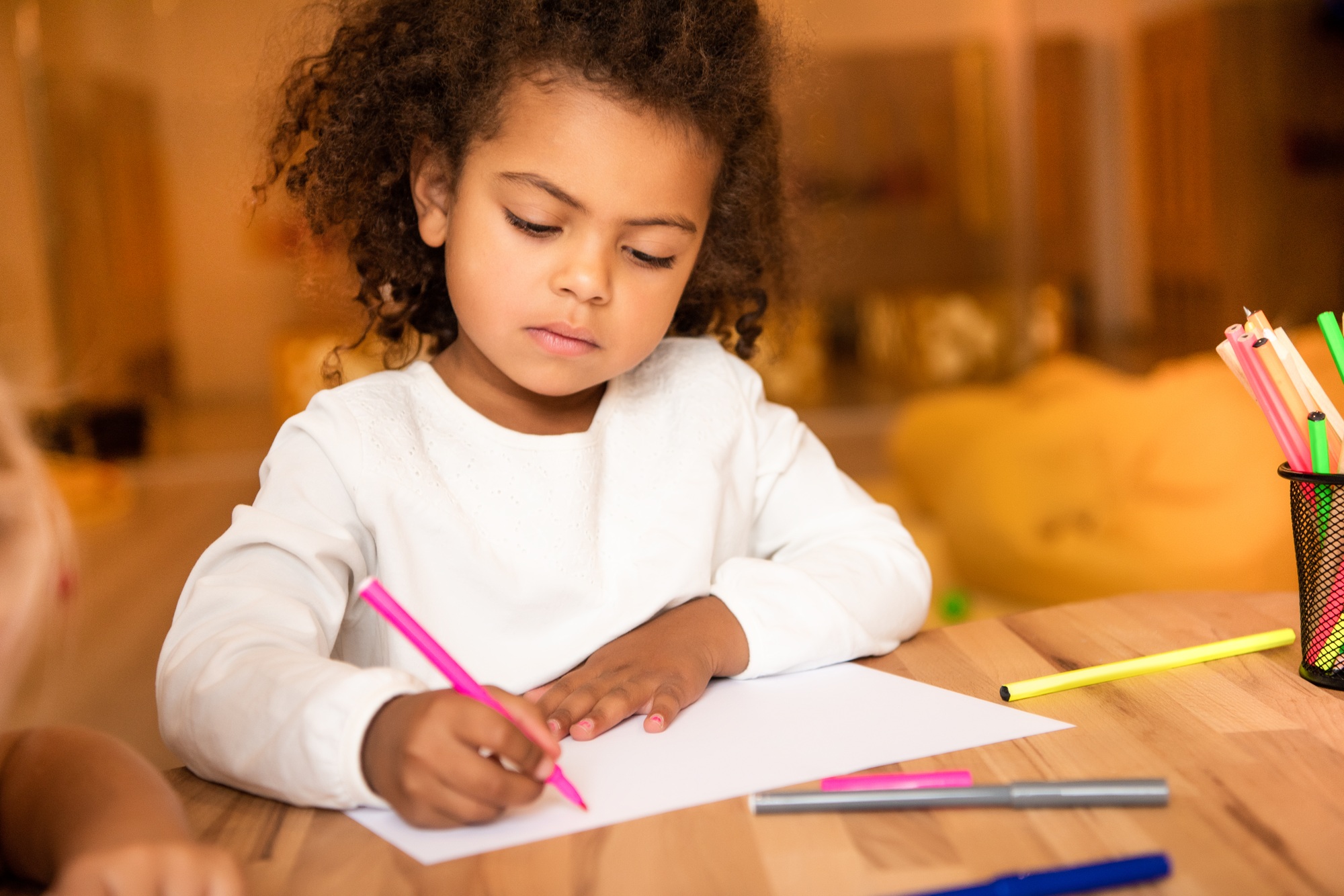 adorable african american kid drawing with pink felt pen in kindergarten
