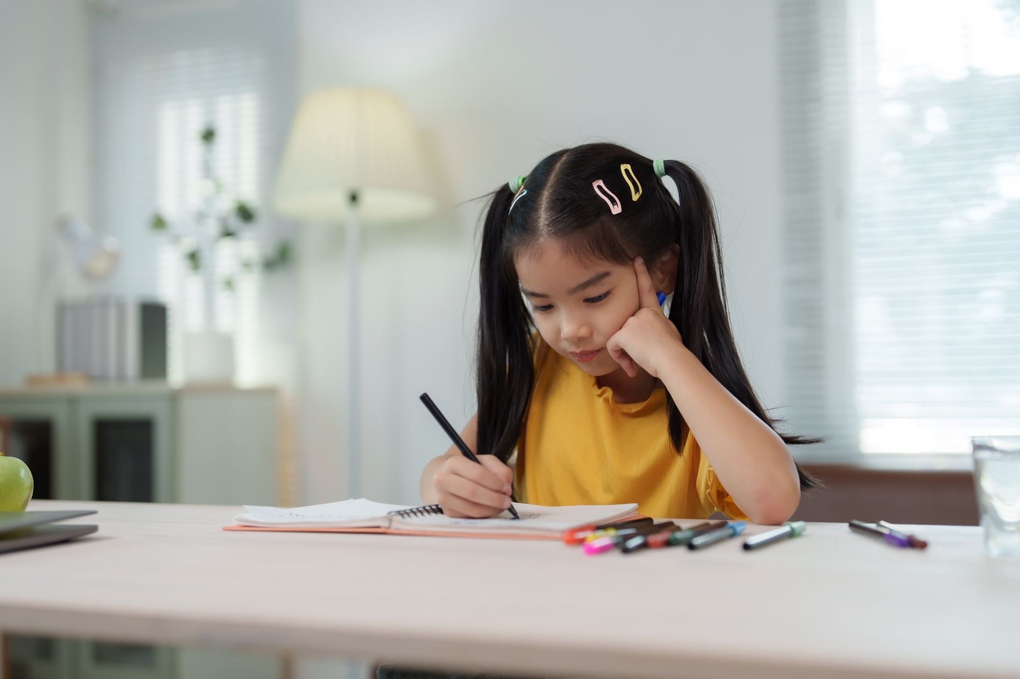 Asian girl drawing and painting at home with colored pencils