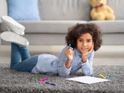 Black girl drawing on paper with colorful crayons