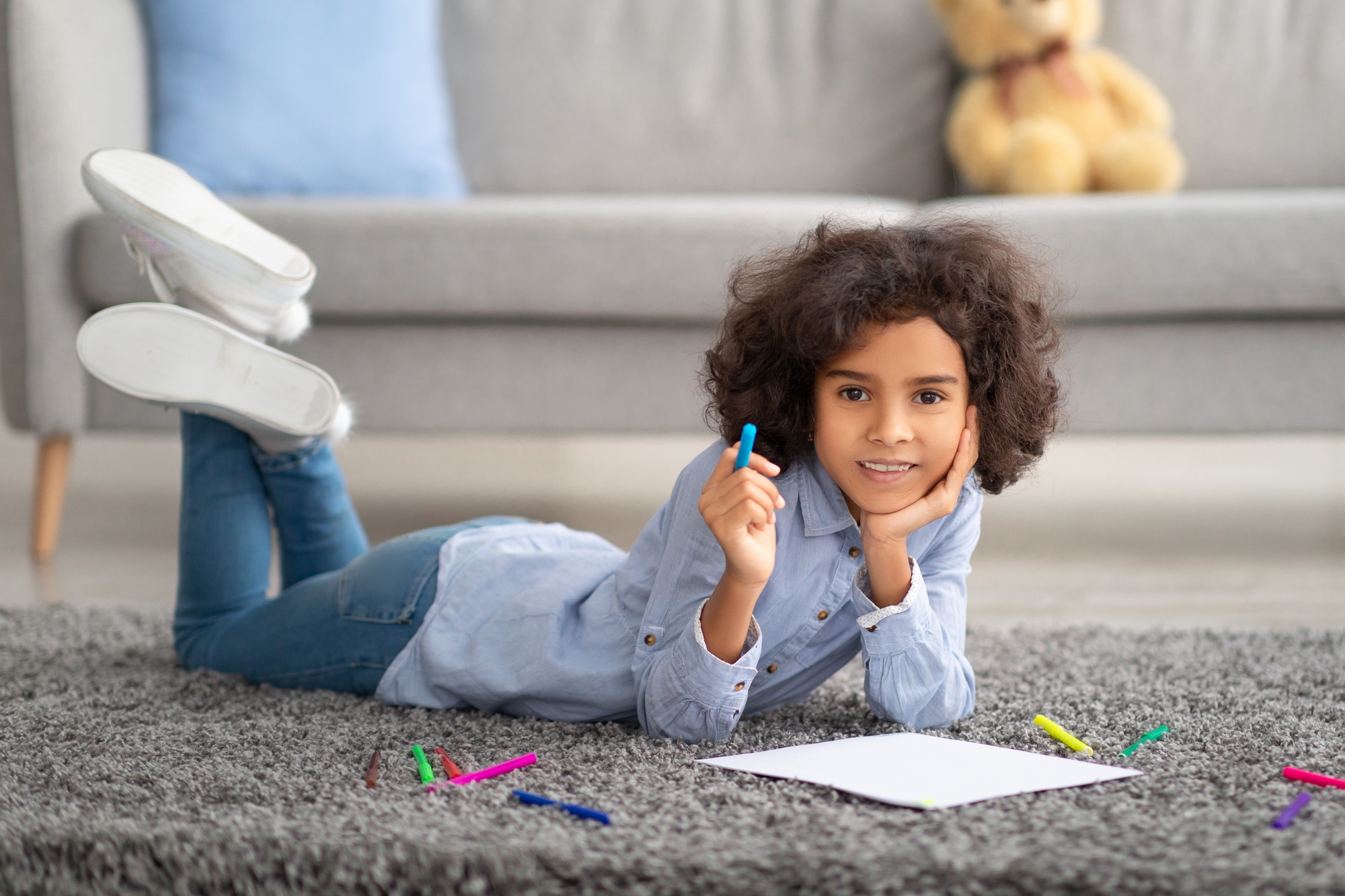 Black girl drawing on paper with colorful crayons