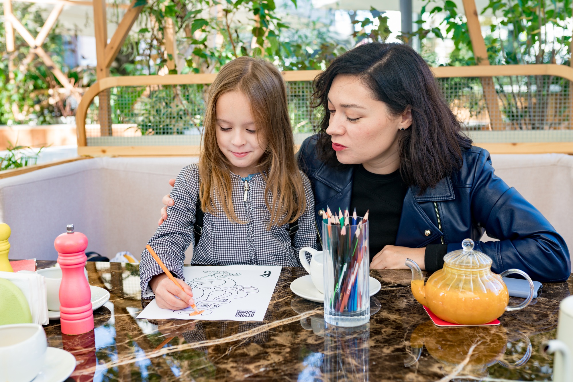 Child girl drawing coloring book in cafe