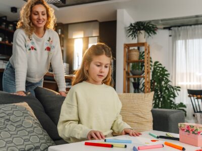Daughter drawing heart for mother's day with colorful markers at home