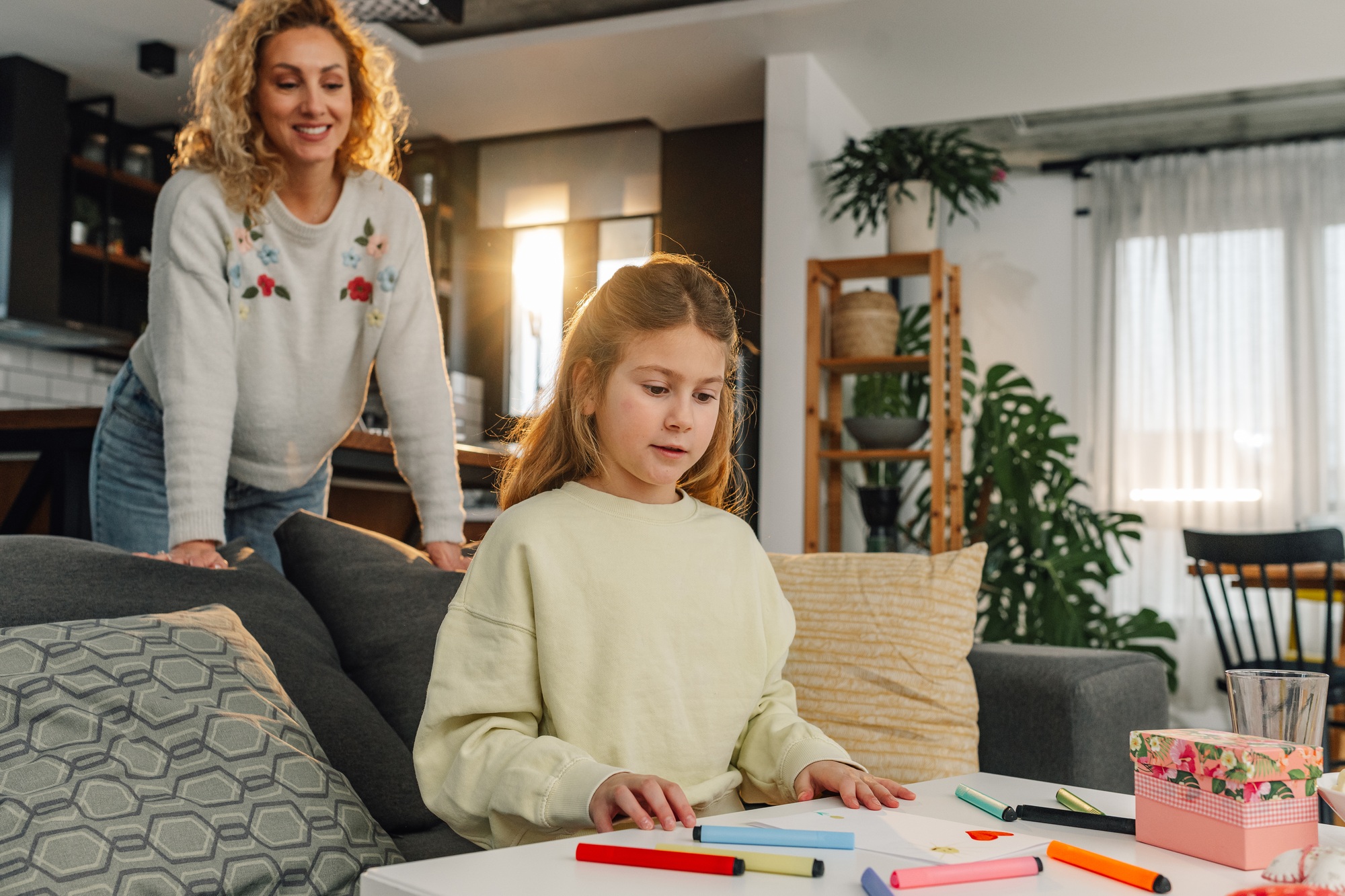 Daughter drawing heart for mother's day with colorful markers at home