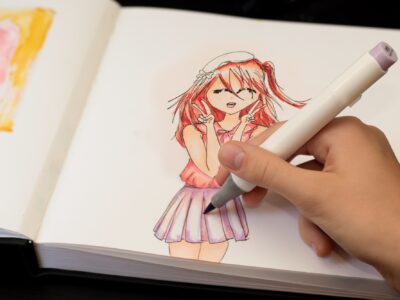 Girl's hand drawing anime manga sketch with alcohol based sketch markers.