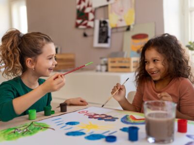 Happy little girls painting picture during creative art and craft class at school