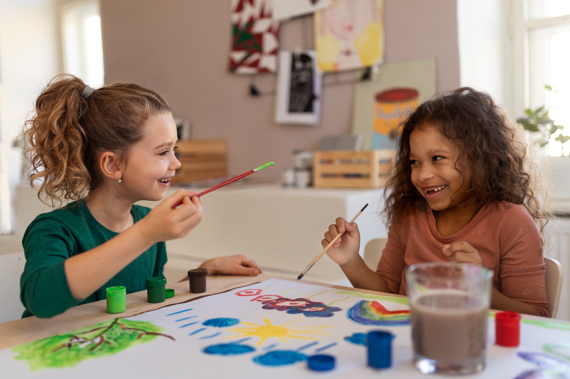 Happy little girls painting picture during creative art and craft class at school
