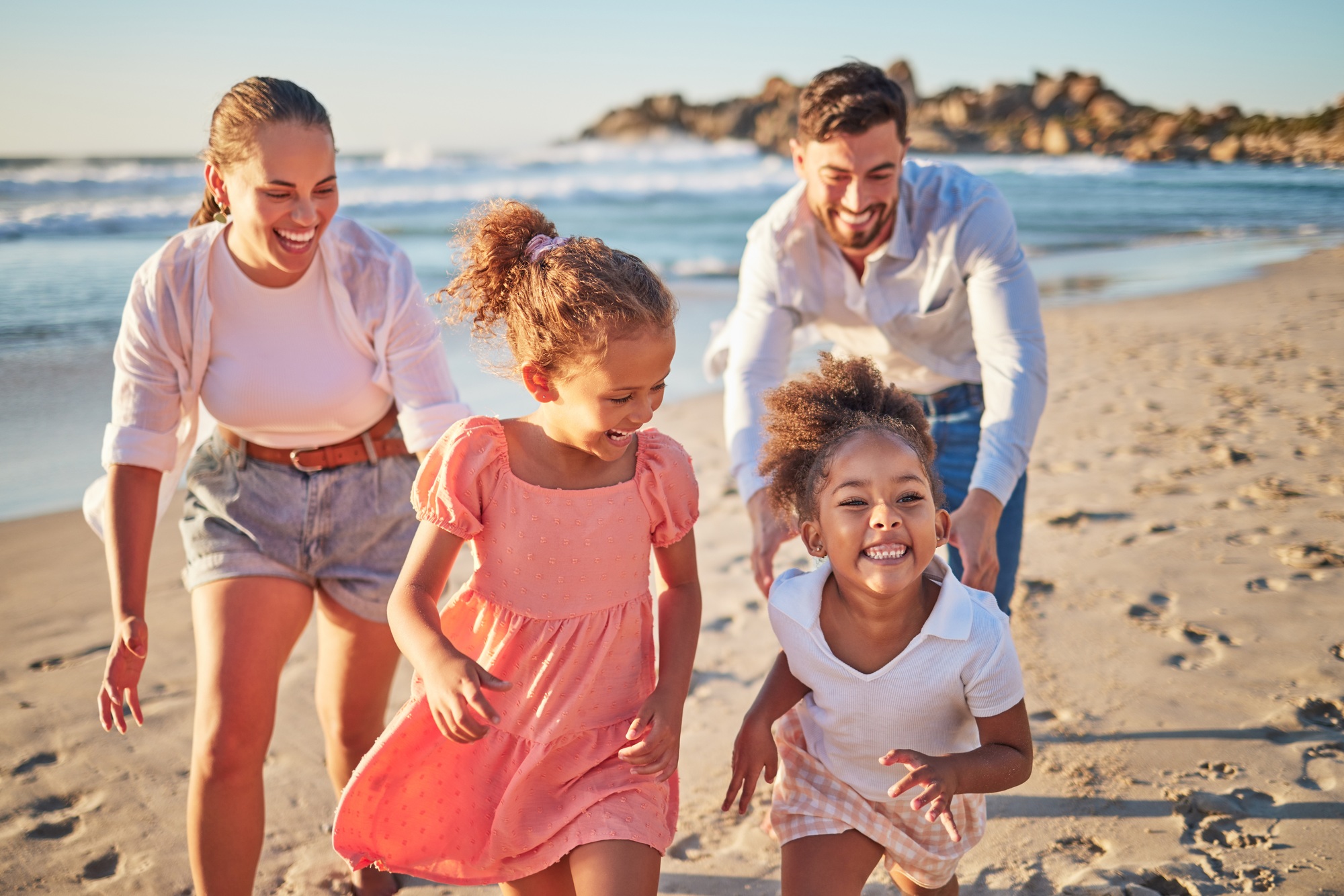 Ocean, holiday and happy family running on beach on a summer vacation. Mom, dad and girl children l