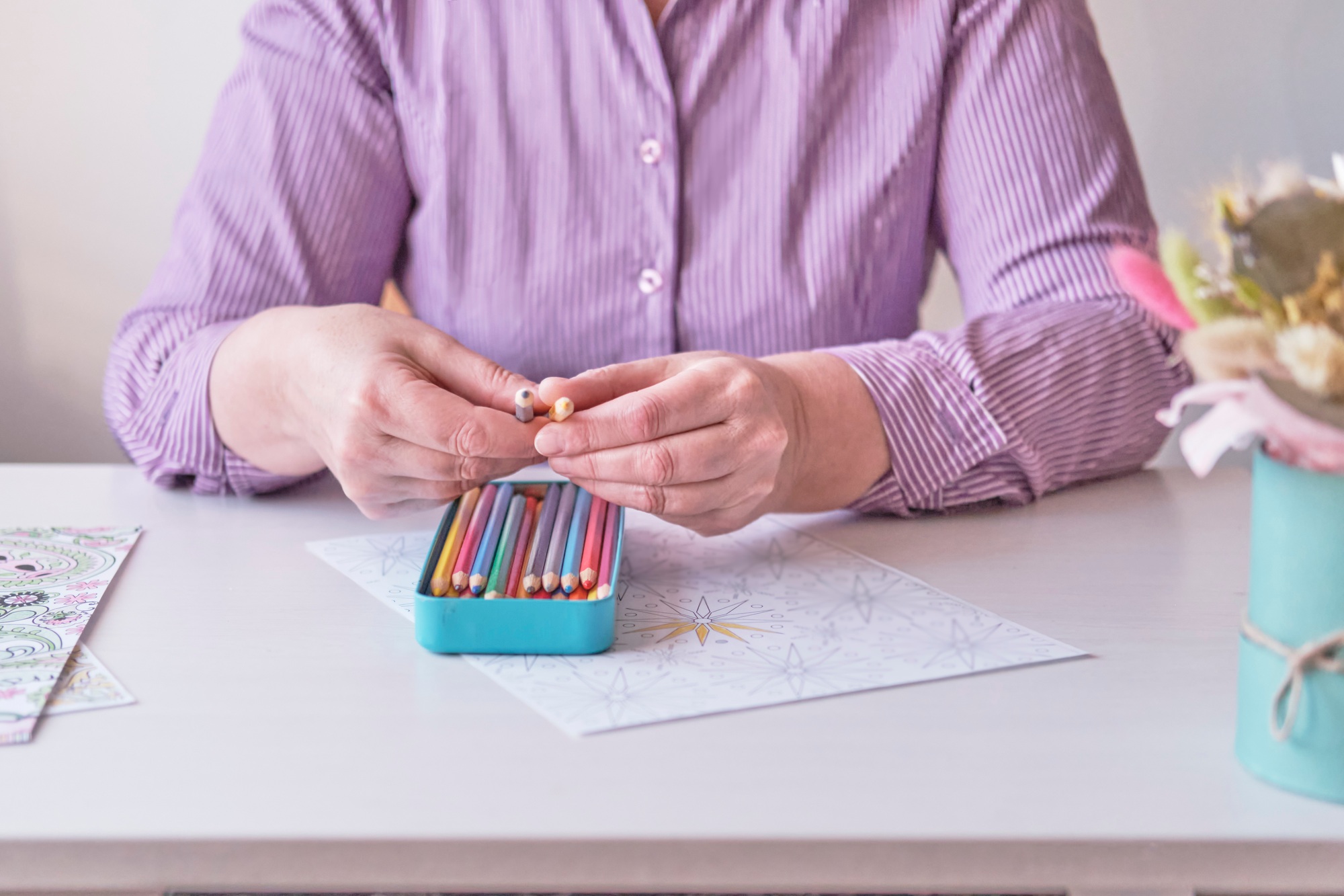 Senior woman's hands selecting the colored pencils for painting pages from adult coloring pages.